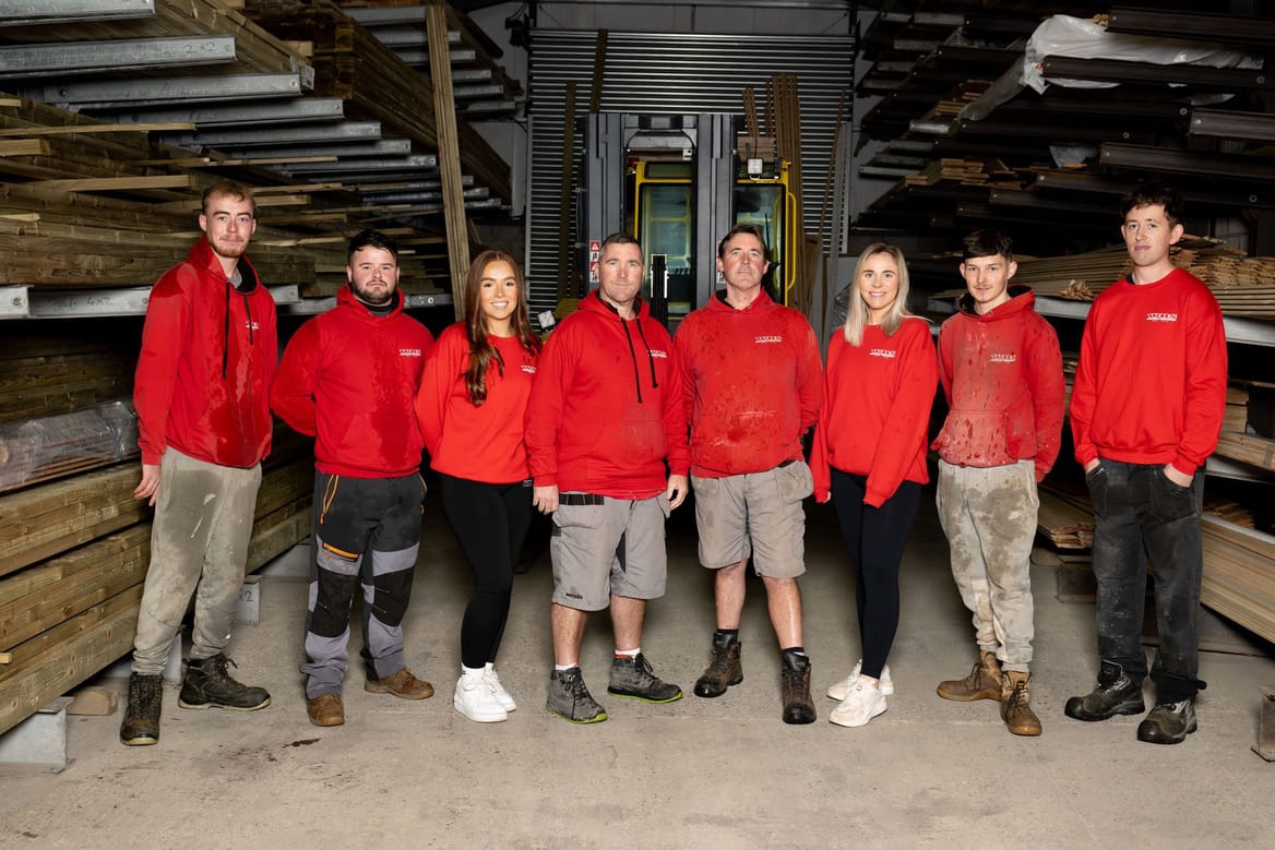 A group of people in red shirts standing in a warehouse.