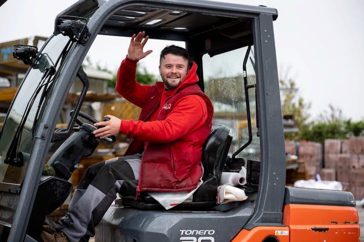 Man waving from the driver's seat of a forklift.