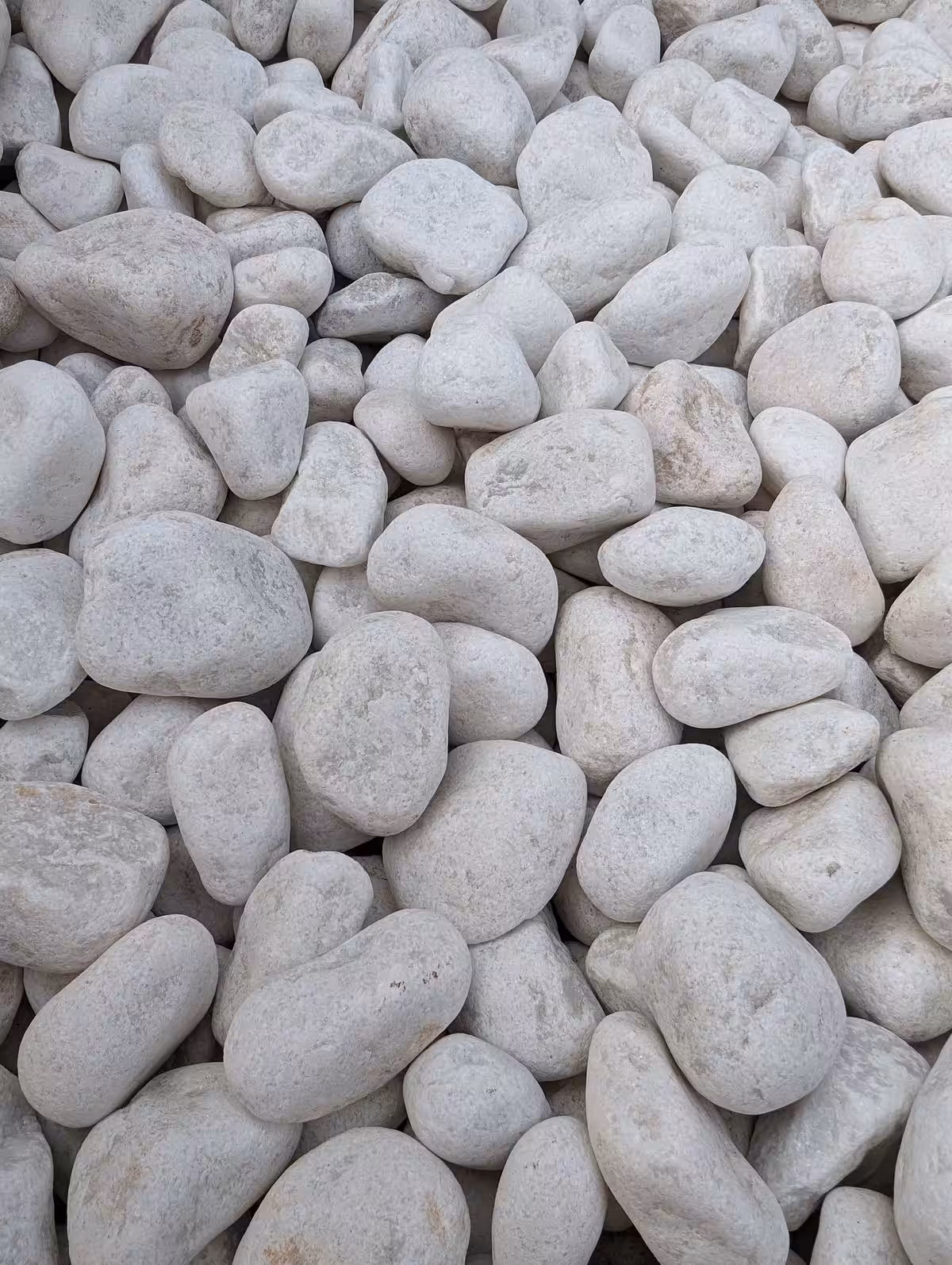 Close-up of a pile of Polar White Pebbles, smooth and varying in size.
