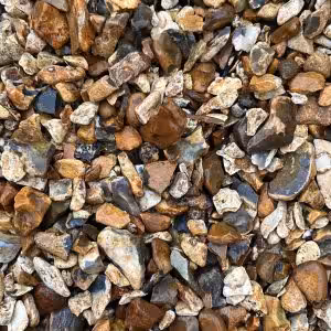 Close-up of a pile of Cotswold Flint Gravel (20mm), featuring small, irregularly shaped rocks and pebbles in various shades of brown, gray, and tan.