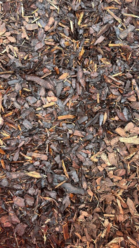 Close-up of a pile of bark mulch with varying shades of brown, showcasing rough, jagged wood chips.